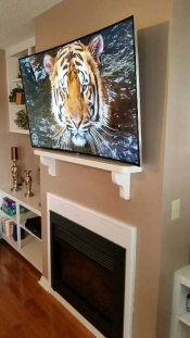 Photo of a curved TV mounted over a fireplace mantel with all wires hidden